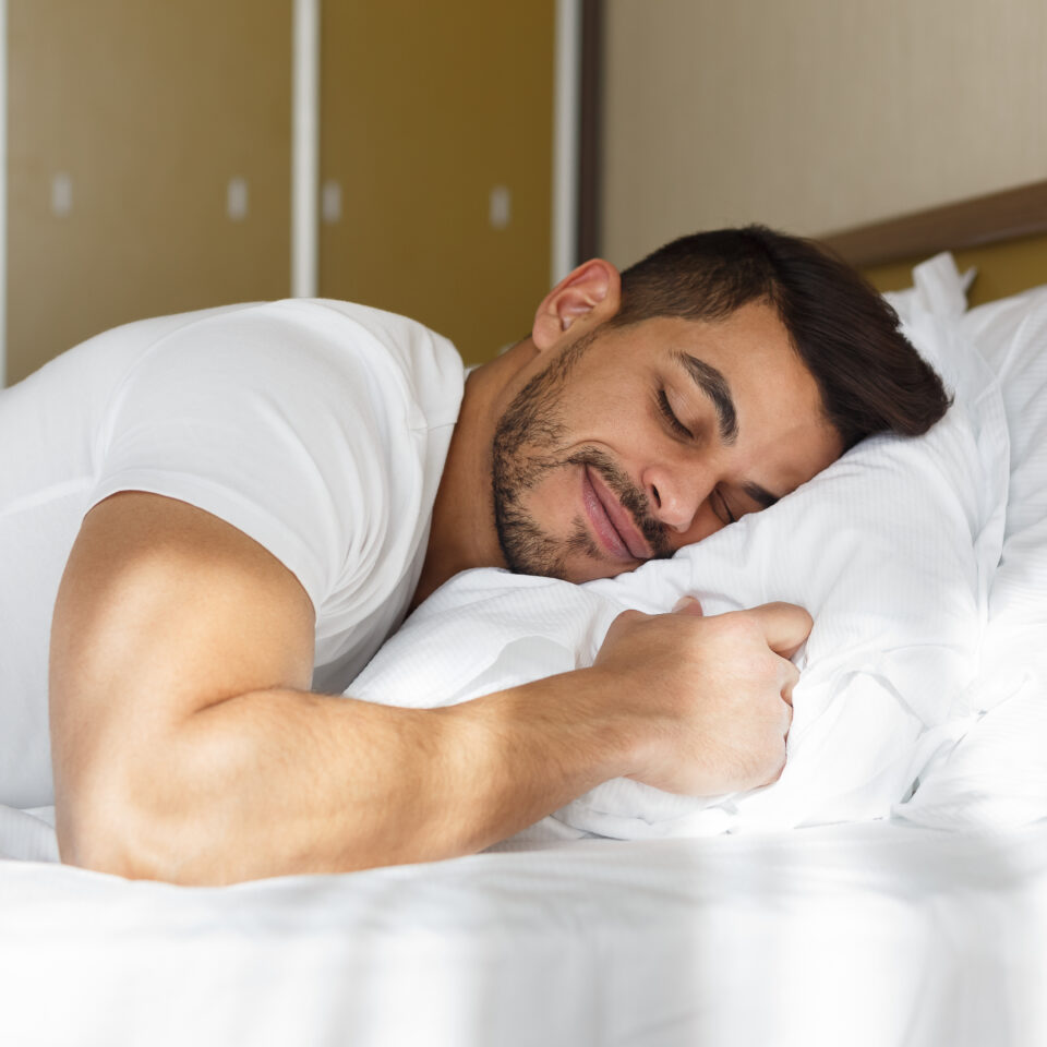 Young eastern man peacefully sleeping in his bed, panorama with copy space