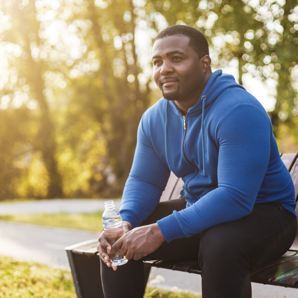 Man resting on bench after exercise and  drinking water .