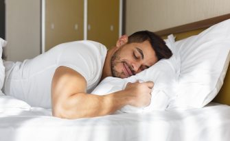 Young eastern man peacefully sleeping in his bed, panorama with copy space